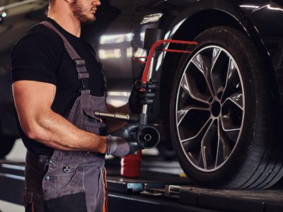 muscular-man-is-fixing-car-s-wheel-with-special-tool-at-auto-service